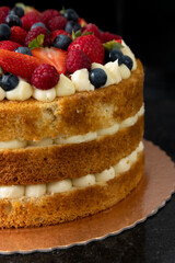 Red berries Naked cake with white cream and flowers to decor 