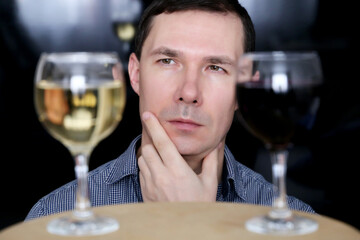 Choosing alcohol, man looks at the glasses with white and red wine. Tasting and party concept