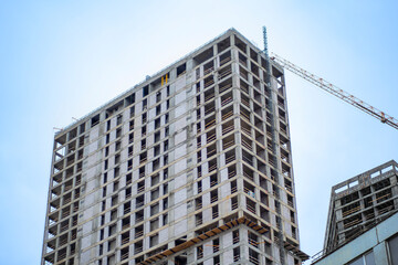 Fototapeta na wymiar Residential high-rise building under construction. Unfinished house on a construction site with cranes.