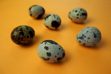 Obraz premium six raw little quail eggs lie on an orange background side view