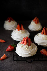 Anna Pavlova cake with cream and fresh strawberries on a dark background
