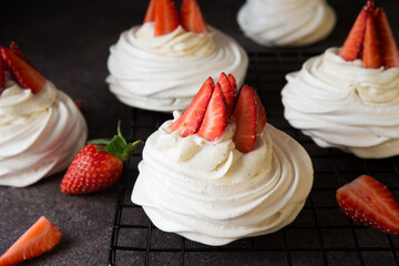 Anna Pavlova cake with cream and fresh strawberries on a dark background