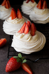 Anna Pavlova cake with cream and fresh strawberries on a dark background,
