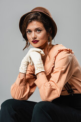 pretty woman in hat, gloves and vintage blouse looking at camera isolated on grey