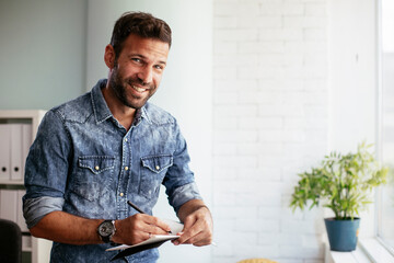 Handsome businessman sitting on a desk, writing notes. Businessman making businessplan..