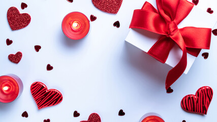 Saint Valentine day: red love hearts, romantic gift box, candle on white background. Romantic message template with copy space. Flat lay, top view, copy space.
