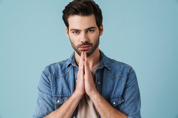 Young handsome unshaven man holding palms together