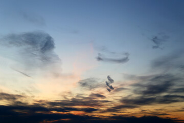 Sunset on colorful dramatic sky, dark cirrus clouds in the pink and orange sunlight. Picturesque landscape for background