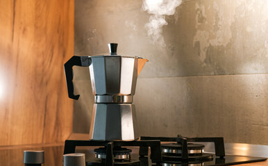An Italian espresso mokka machine with steam getting out of it while making a fresh coffee in a...