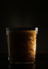 Close up view of jar full with Rotelle Wagon wheel-shaped pasta against dark background