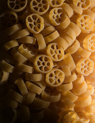 Close up view of jar full with Rotelle Wagon wheel-shaped pasta against dark background