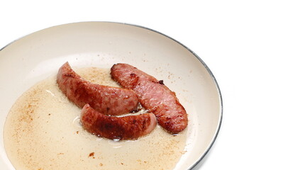 Fried sausages in frying pan isolated on white background