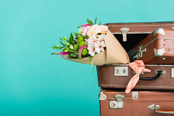 bouquet of fresh flowers and vintage suitcases isolated on turquoise