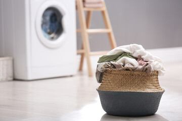 Wicker basket with dirty laundry on floor indoors, space for text