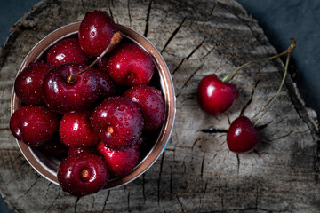 Fresh, clean cherries in a bowl on a wooden board. Photo in a rustic style. Simple and healthy vegetarian food concept