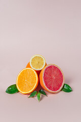citrus fruits, grapefruits, mandarins, lemons, oranges, with green leaves lie on a light background.