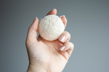 Natural konjac sponge in a female hand for deep cleanse and exfoliate skin. Healthy lifestyle, zero waste cosmetic routine. 