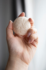 Natural konjac sponge in a female hand for deep cleanse and exfoliate skin. Healthy lifestyle, zero waste cosmetic routine. 