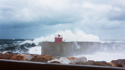 Obraz premium Breaking wave over the harbor light