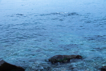 Obraz premium beautiful, blue sea with waves, foam, rocks at the beach in good weather in the evening