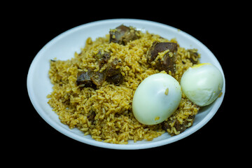 mutton biriyani with egg served in a serving white plate on black background
