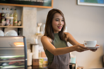 Beautiful young Asian woman offering a cup of coffee.