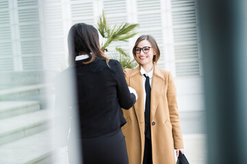 colleghe manager si incontrano in contesto business in esterni vicino ad un palazzo moderno fatto...