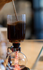 Professional barista preparing coffee. Alternative ways of brewing coffee. Close up of coffee brewing gadgets on wooden bar counter. Coffee brewed in low light in the house. 
