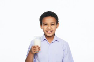 African American male kid holding a glass of milk with a toothy smile, isolated on white background. Benefits of milk for kids