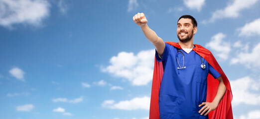 healthcare, profession and medicine concept - happy smiling doctor or male nurse in blue uniform and red superhero cape with stethoscope over blue sky and clouds background © Syda Productions