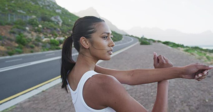 African american woman wearing sportswear performing stretching exercise on the road