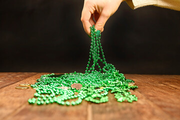 St. Patrick's concept. A woman's hand picks up green clover necklaces.