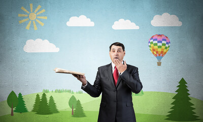 Surprised businessman holding open old book