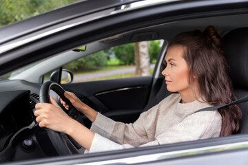 safety and people concept - young woman or female driver driving car in city