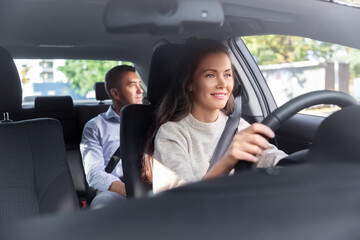 transportation, vehicle and people concept - happy smiling female driver driving car with male...