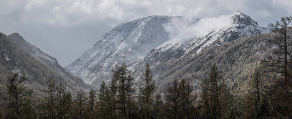 Panoramic mountain view, snow-capped peaks, cloudy weather