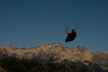 back shot of paraglider flying towards the mountain with copy space