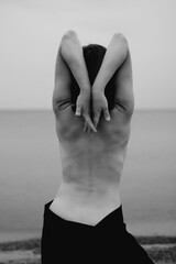 Woman's naked back with raised arms, black and white photo