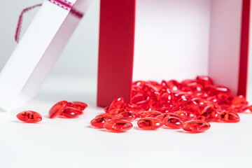 wrap the red and white gift with a ribbon on a bright background. A gift box with red glass hearts inside.