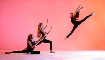 group of three ballet girls with long flowing hair in black tight-fitting suits dance on red background