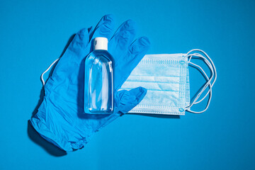 Medical gloves mask and alcohal gel for protecting infection during Coronavirus pandemic top view on light blue banner background