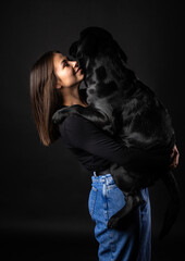 A girl holds a Labrador Retriever dog in her arms.