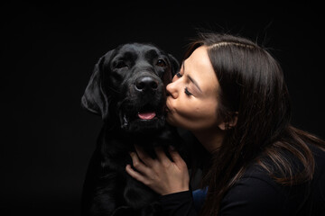 A girl holds a Labrador Retriever dog in her arms.