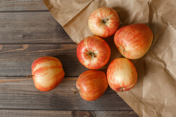 Red apples in a paper bag wooden background