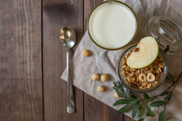 Obraz na płótnie Canvas A glass jar with homemade muesli with nuts and a green apple. Healthy breakfast.