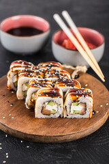 Sushi roll with eel, salmon, cucumber and cream cheese on a dark background close-up.