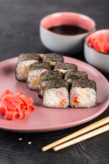 Sushi roll in nori seaweed with caviar and cream cheese on a dark background close-up.