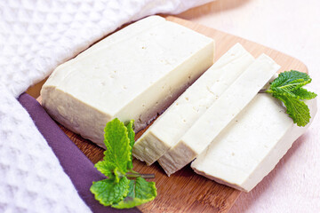 Raw organic vegetarian tofu slices with fresh mint on wooden background.