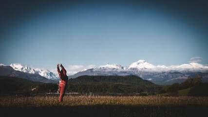 a young girl exercises in a clearing with a view of the snowy mountains