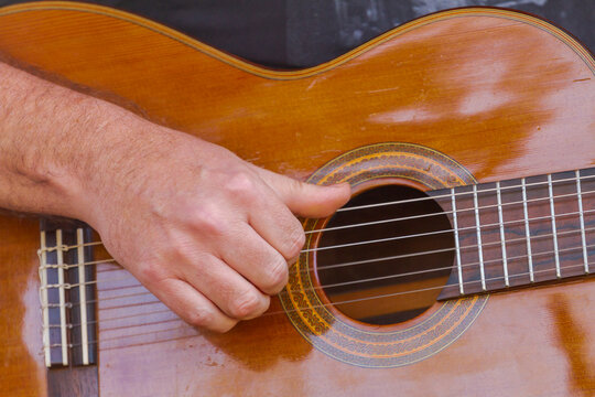 Detalhe de m&atilde;o de m&uacute;sico tocando baixo ac&uacute;stico